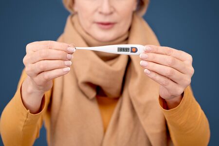 Coronavirus Concept. Blonde woman in scarf standing isolated on blurred blue with electronic...