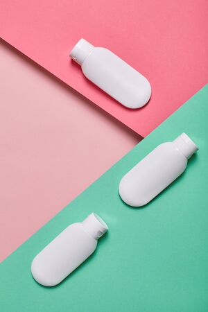 Bottles of anti-aging cream isolated on pink and turquoise background beauty care top view close-upの写真素材