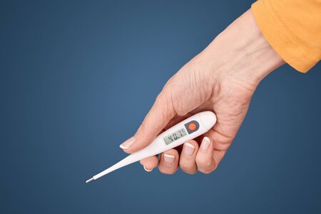 Global epidemic concept. Cropped view of middle aged woman holding electronic thermometer with high...