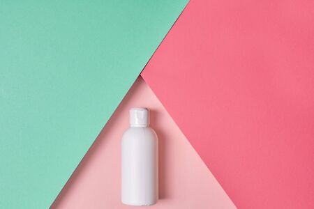 Body care and beauty concept. Top view of moisturizer product in white bottle lying on pastel background with copy spaceの写真素材