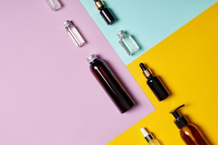 Moisturizer and body care concept. Top view of different plastic bottles and container with liquid lying on pastel colorful backgroundの写真素材