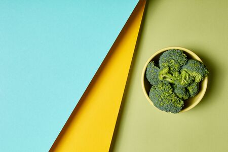 Dieting and healthy food concept. Top view of fresh and green broccoli lying in bowl on pastel colorful background with copy spaceの写真素材