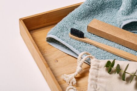 Eco-friendly bamboo toothbrush on wooden tray with towel morning groomingの写真素材