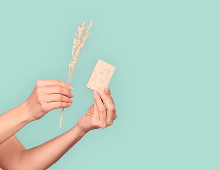 Beautiful mature woman standing isolated on blue background holding wheat and organic natural soap close-up copy space for text or productの写真素材
