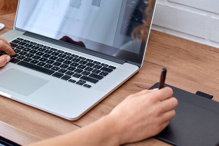 Cropped view of young adult freelance girl working with modern laptop and tablet computer at home, creating online products and media contentの写真素材