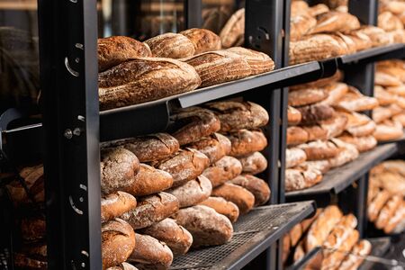 Concept of small bakery. Selective focus on fresh, crispy and perfect wholegrain bread lying on shelves with homemade loaves at kitchenの写真素材