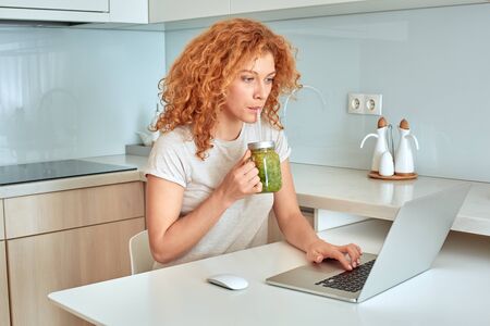 Young adult girl using laptop and drinking smoothieの写真素材