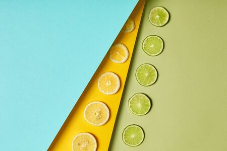 Minimal food healthy flat lay, green lime, yellow lemon slices pattern on colored background. Paper texture, Top view concept with copy space. Fresh ingredients for juice, cocktails or smoothie. Detoxの写真素材