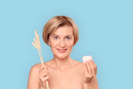 Mature aged female holding herbs and cream in handsの写真素材