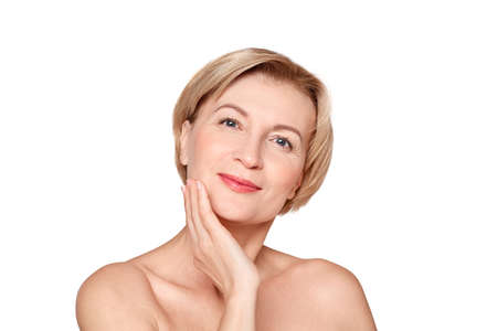 Mature aged woman touching her cheek, looking at cameraの写真素材