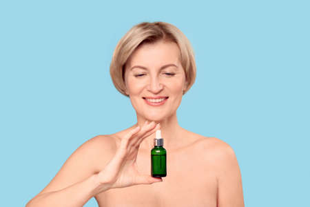 Middle aged female holding organic rejuvenation oil in glass bottleの写真素材