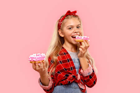 Child girl biting sweet donut and smiling wideの写真素材