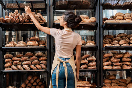 Young adult woman standing near fresh baked breadの写真素材