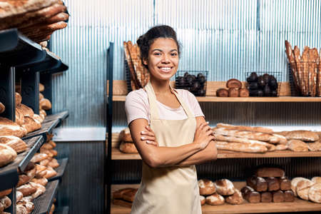 Young adult woman standing in family bakeryの写真素材