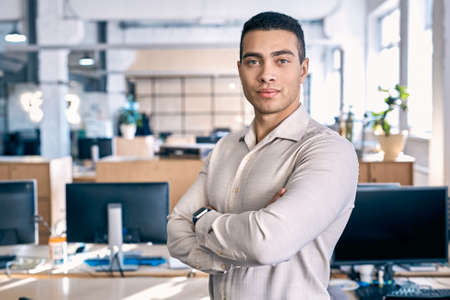 Business Concept. Man in shirt standing close-up on office background crossed arms smiling confidentの写真素材