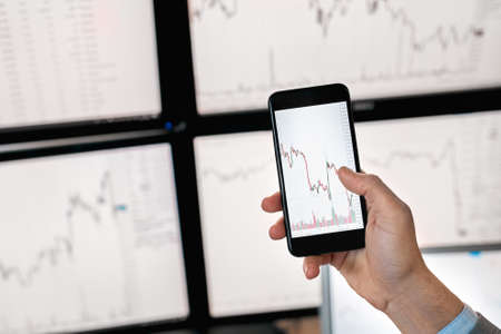 Trader holding smartphone with mock up of index on cryptocurrency diagramの写真素材