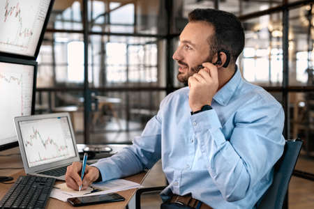 Businessman talking on headset, analyzing index on cryptocurrency diagramの写真素材