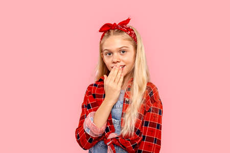 Freestyle. Little girl in bandana on head standing isolated on pink covering mouth surprisedの写真素材