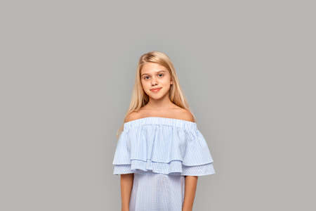 Young girl standing in studio and smiling wideの写真素材