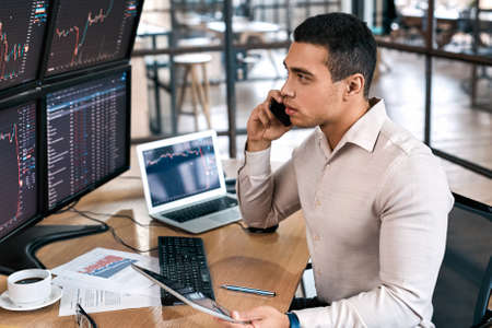 Businessman checking cryptocurrency information data, talking on smartphone