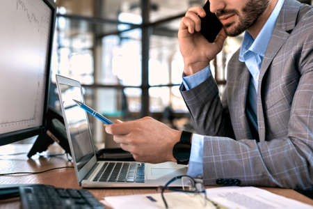 Businessman checking cryptocurrency information and talking on smartphone