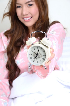 A girl show the alarm clock in her hand, that time on seven oの写真素材