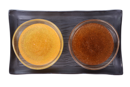 Two different of scrub oil, honey and sugar cane, for skin treatment on black ceramic plate.の写真素材
