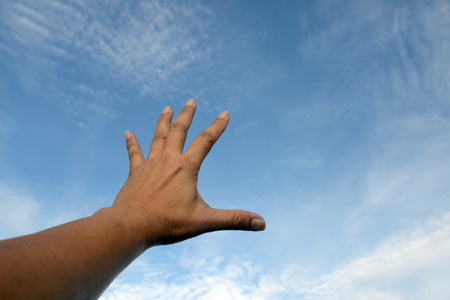Raise one's hand reach out for something from the bright blue sky.の写真素材