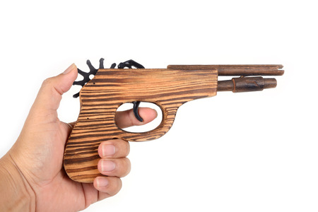 Wooden toy gun in someone hand on white background.の写真素材
