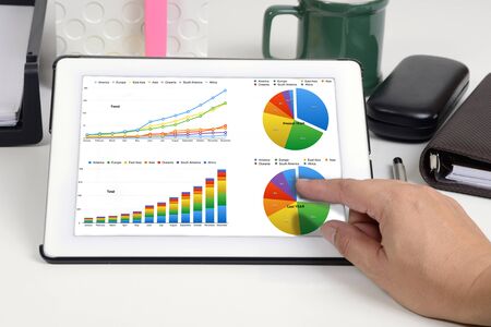 Someone working on business report that shown by chart on tablet.の写真素材