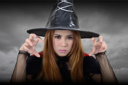 Witch looking toward and try to casts a spell in dark background.
