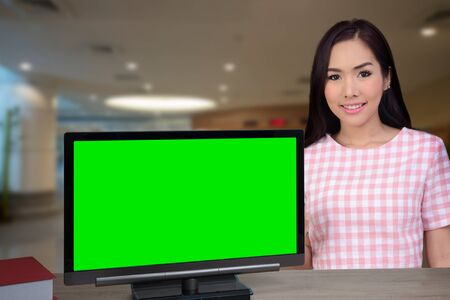 Woman standing at front desk and computer monitor that show green screen in lobby.の写真素材