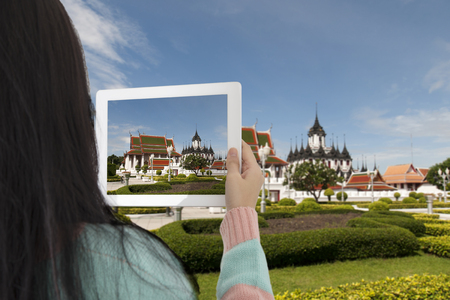 Tourist girl taking photo of Maha Jessada Bodin Pavilion and Metal Castle famous landmark in Bangkok Thailand by tablet.の写真素材