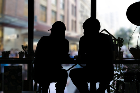 Shadow of couple sitting in coffee shop and looking out of windows.の写真素材