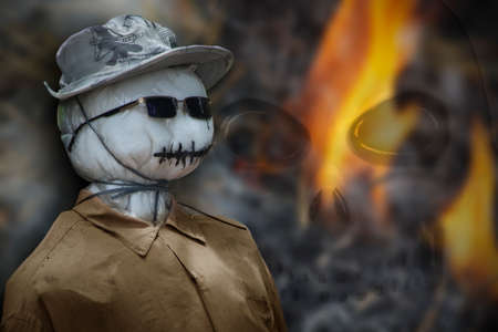 Scarecrow face with fire and skull in background.