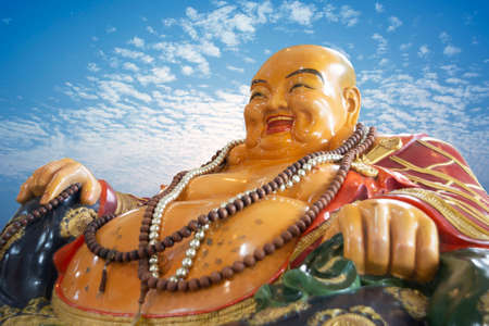 Smiling Buddha, god of happiness, wealth and lucky on blue sky backgroundの写真素材