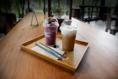 Two cup of beverages served on the tables in the coffee shop room decorated in tropical style.の写真素材