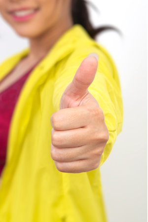 Close up female hand in yellow tracksuit show her thumb up.の写真素材