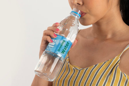 Woman drinks water from PET bottle that is clean drinking water and free from germs and impurities on white background.の写真素材