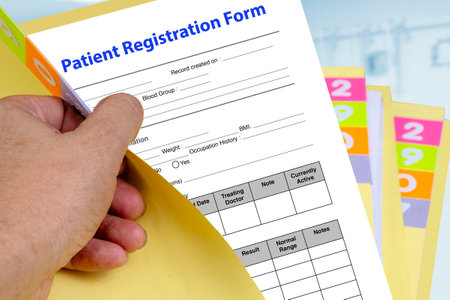 Hand open yellow medical record folder then revealing patient registration form.の写真素材