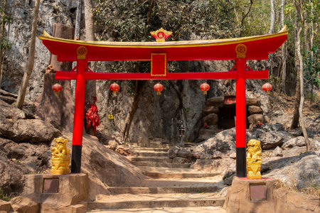Red Chinese style archway entrance to a religious site located at the foot of a mountain.の写真素材