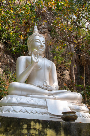 A large silver Buddha statue is enshrined at the foot of the mountain in the outdoors.の写真素材