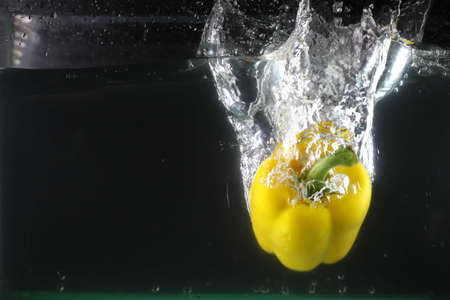 Yellow sweet pepper dropped into water and created a water splashの写真素材