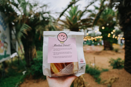 Jeju, South Korea - July 11, 2022: Package of donuts on hand at Cafe Knotted Jeju Aewol branch.のeditorial素材