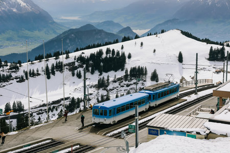 Rigi, Switzerland - April 12, 2022: Blue electric cable tram of Rigi kulm line with alps mountain in background.のeditorial素材