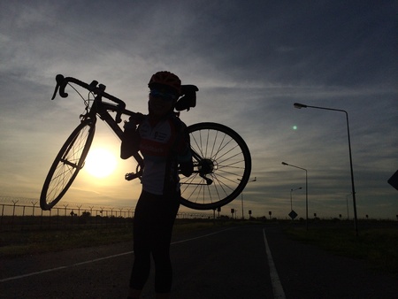 Rider in a shadow lifting up toad bike with sunrise backgroundの素材