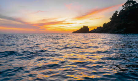 Blur background of indigo blue ocean in the evening, the sun was setting, reflections fell on the wave surface with golden warm light. The sky is clear and clean. Feeling refreshed and relaxed.の写真素材