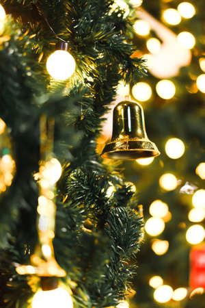 Close up picture of Christmas trees with yellow lights and a bell at night. There is much circular bokeh with warm tones. Feeling happy and cute. The idea for celebration wallpaper with copy space.の写真素材