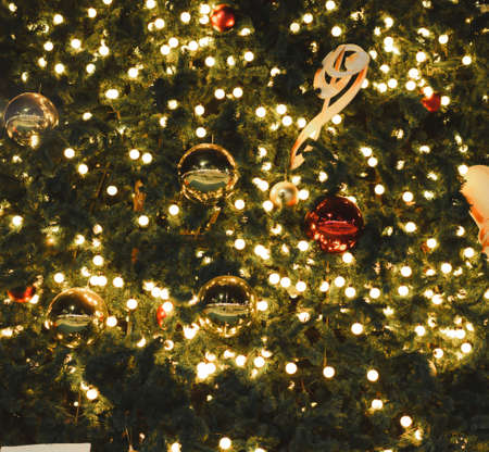 Close up picture of Christmas trees with yellow lights and a bell at night. There is much circular bokeh with warm tones. Feeling happy and cute. The idea for celebration wallpaper with copy space.の写真素材