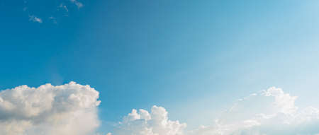 Background picture low angle of bright blue sky on a sunny day. There are fluffy white clouds and clear. Blue and white color contrast in soft tones. feeling fresh and relax. There is a copy space.の写真素材